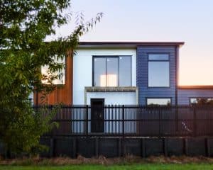 Contemporary modern house with colourful facade, large windows, and black fencing in a suburban neighbourhood.
