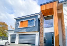 Modern contemporary house with colourful cladding and large windows in a suburban neighbourhood.