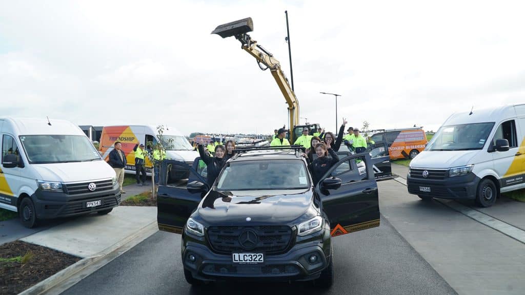Friendly community team celebrating success with new vehicle and outdoor event.