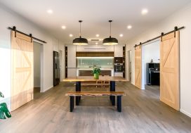 Modern open-plan kitchen with wooden accents, sliding barn doors, and stylish lighting.
