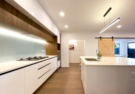 Modern NZ kitchen with white cabinetry and wooden accents, ideal for supportive social gatherings.