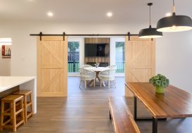 Modern open-plan living and dining space with natural wood accents and sliding barn doors for a stylish, welcoming home.