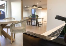 Modern living room with musical keyboard and dining area in a friendly community space.