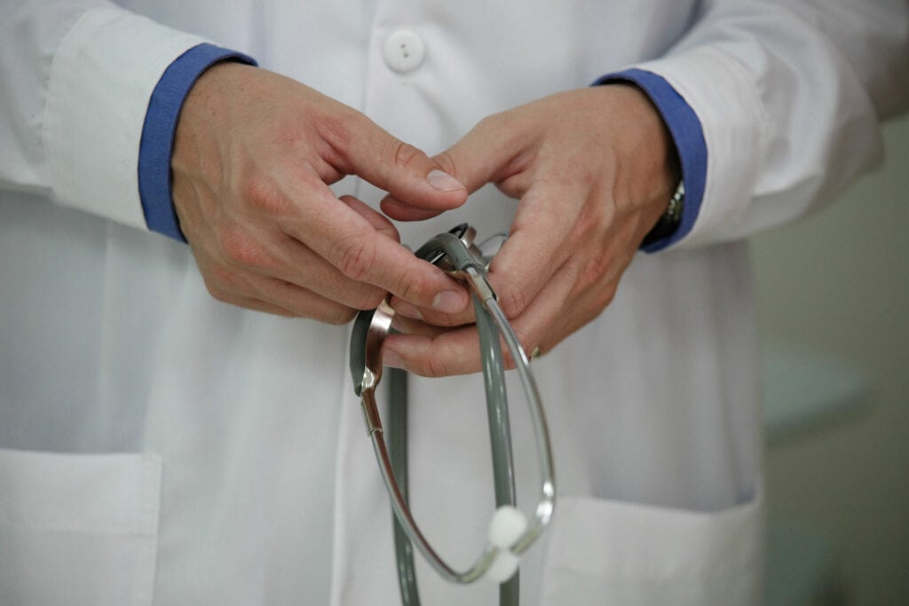 Doctor holding stethoscope in a clinical setting.