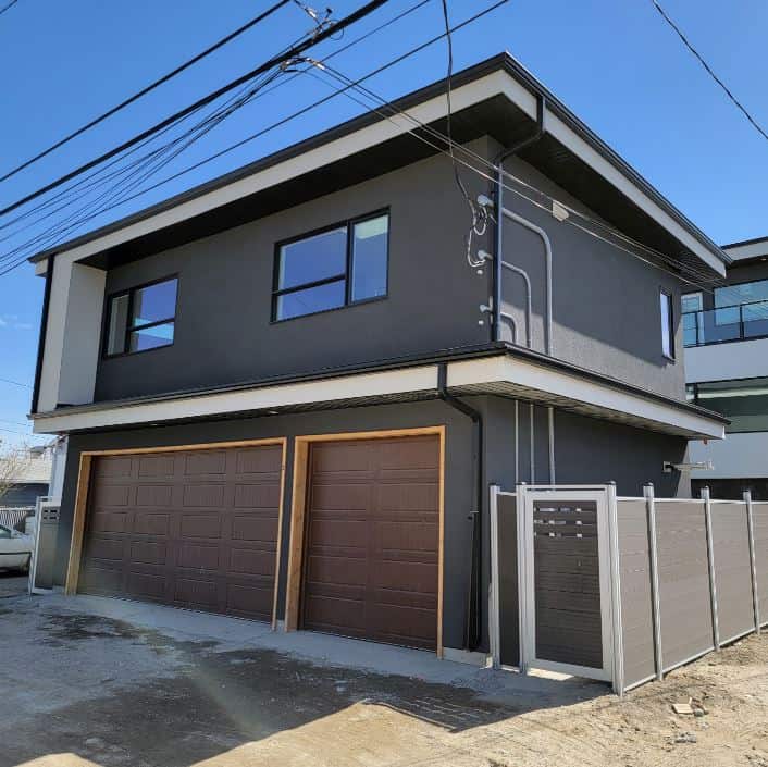 Contemporary black and white house with double garage and secure fencing.