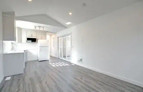 Spacious kitchen with white cabinetry, grey flooring, and ample natural light from sliding doors.