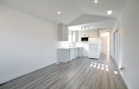 Bright and spacious kitchen with white cabinetry, stainless appliances, and a view of entrance.