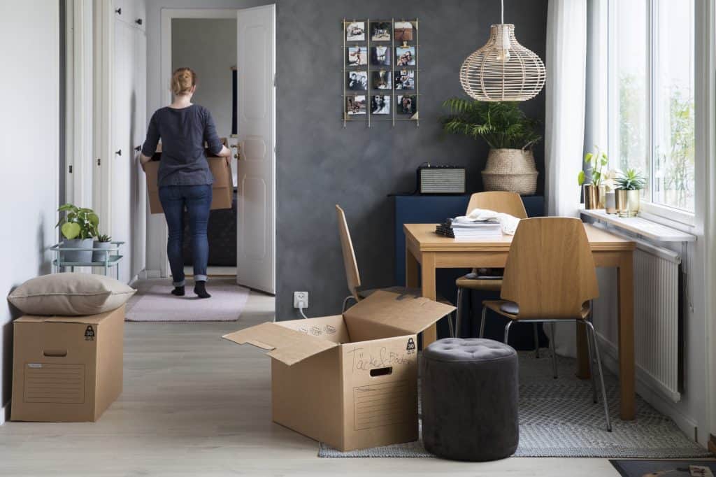 Ett rum med flyttlådor och en kvinna packar upp efter flytt