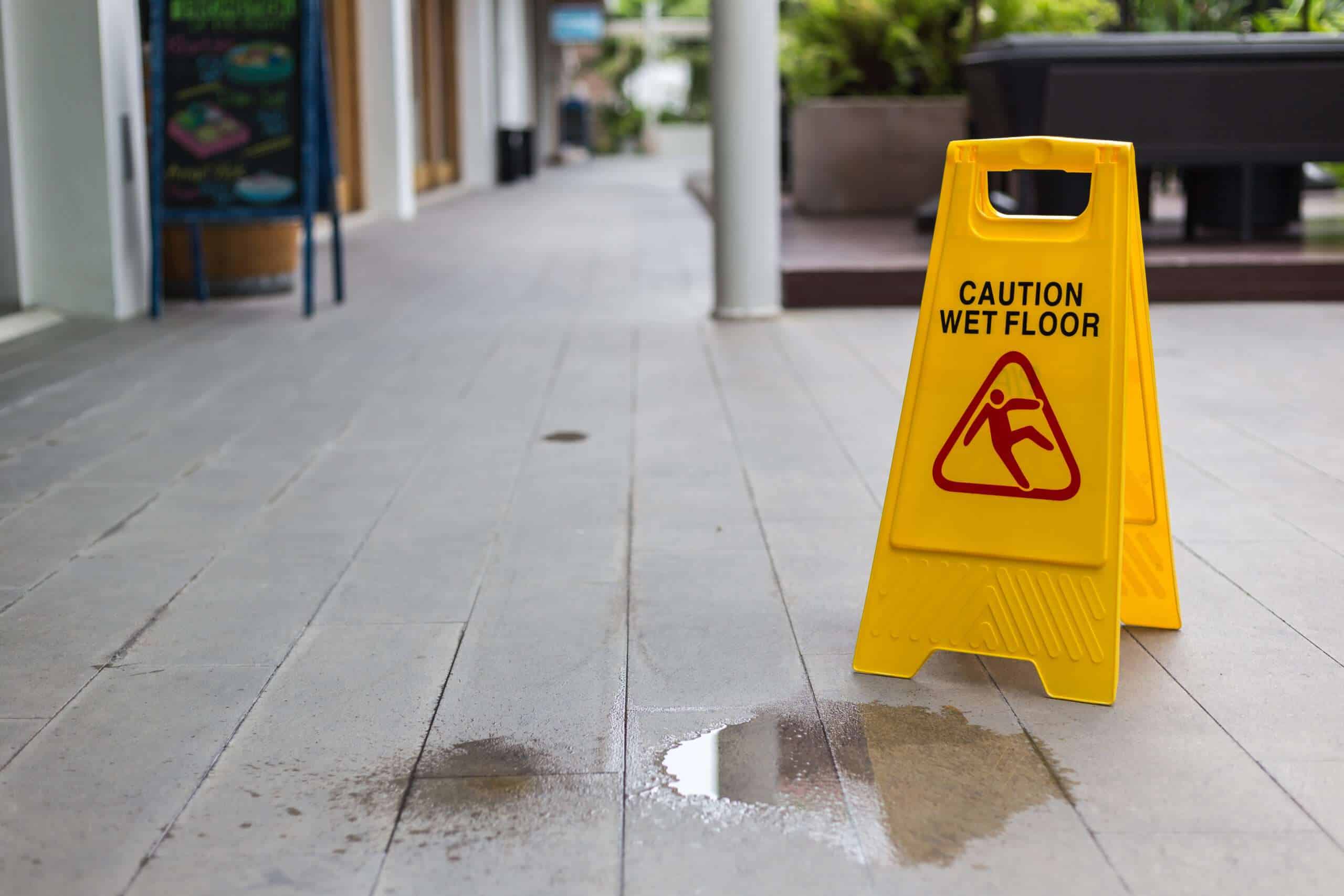 Wet floor caution sign on tile walkway – Boston slip and fall accident lawyer