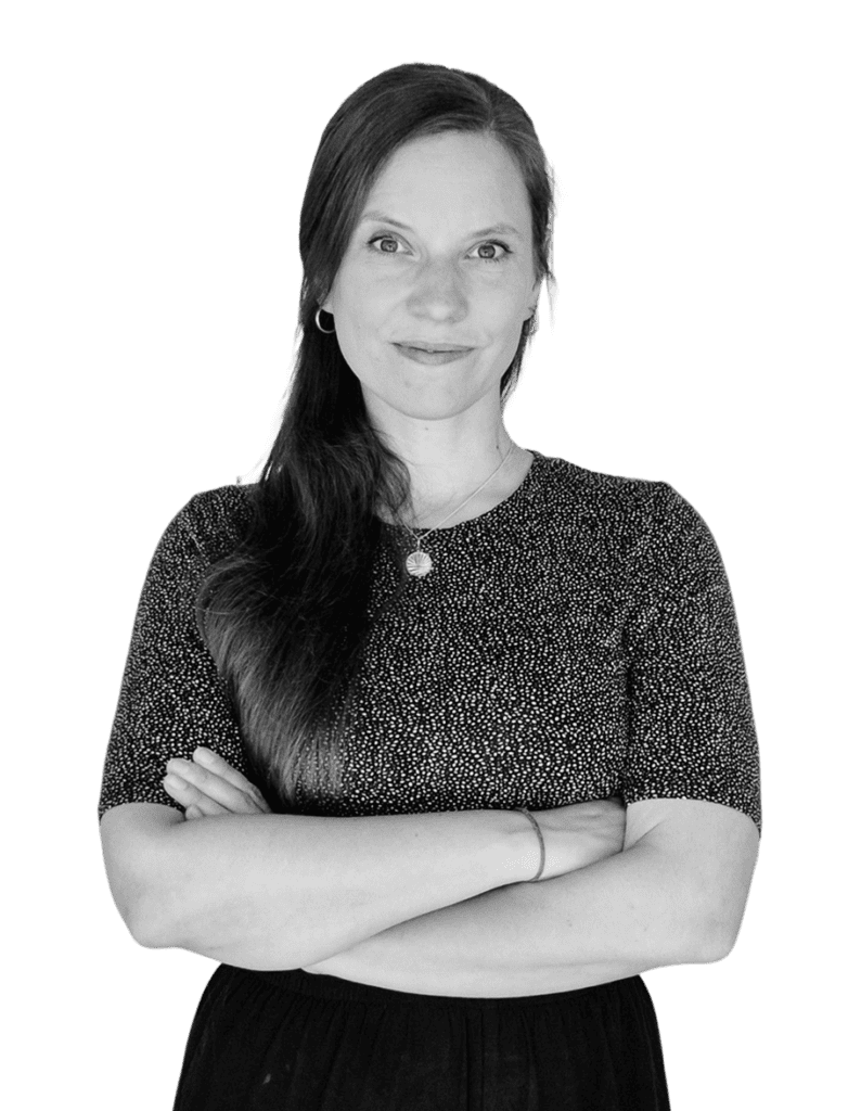Jane in Schwarzweiß. Sie hat die Arme verschränkt und schaut in die Kamera.