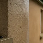 Micro fissure crépi extérieur sur façade, près d’un joint de fenêtre