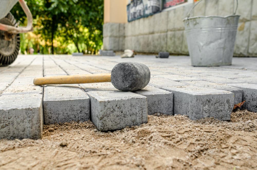 Rubber mallet on grey paving stones being laid on sand