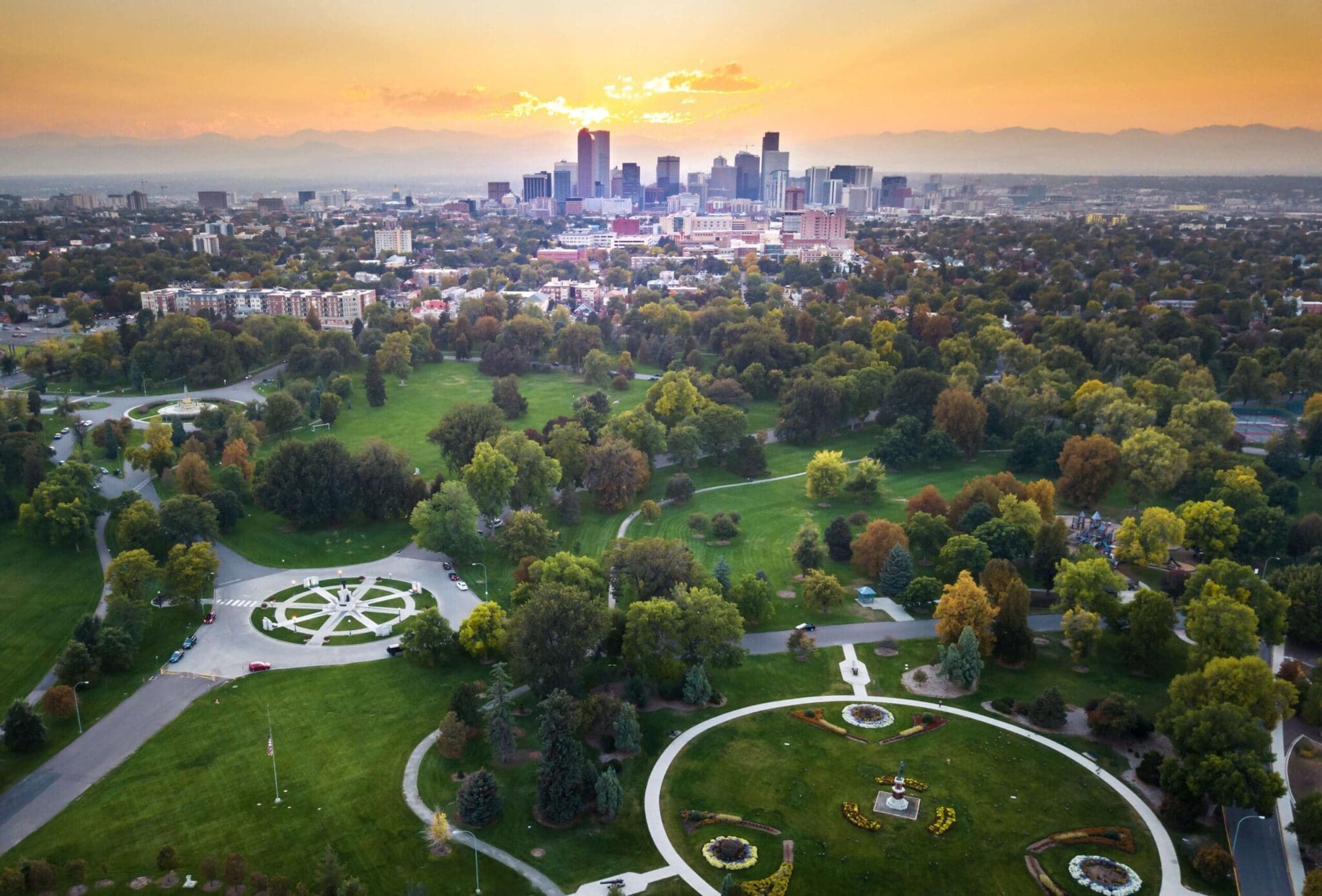 Aerial view of a city skyline at sunset with a park in the foreground.