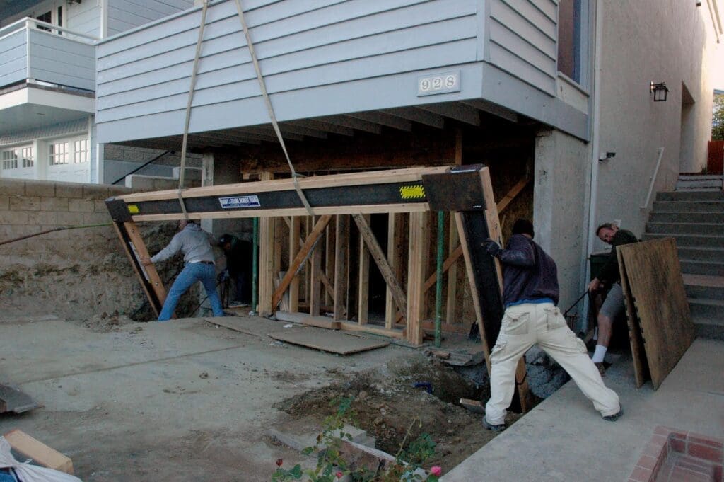 Workers installing a large wooden frame under a house