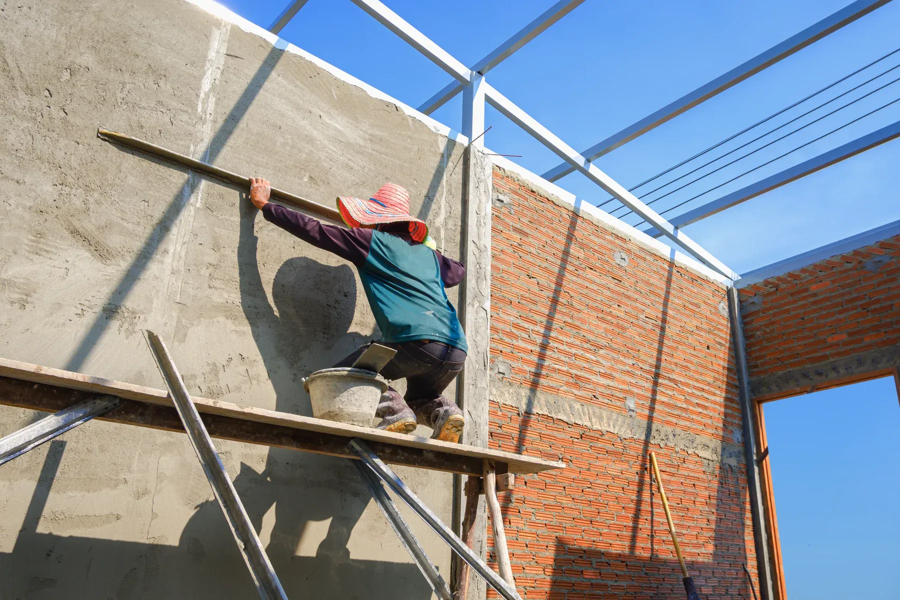 Construction worker plastering a wall on a sunny day