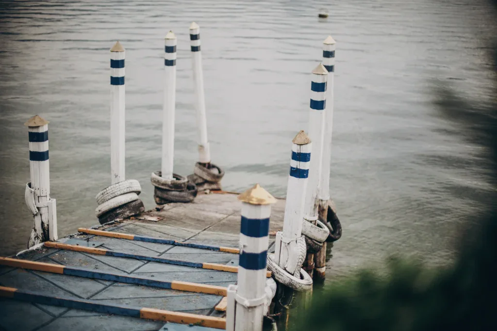 Dock with blue and white striped poles extending into calm water