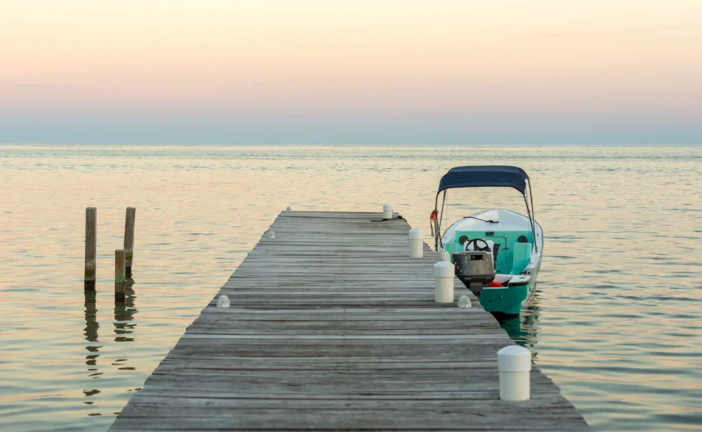 A wooden pier extending into calm water with a small boat docked.