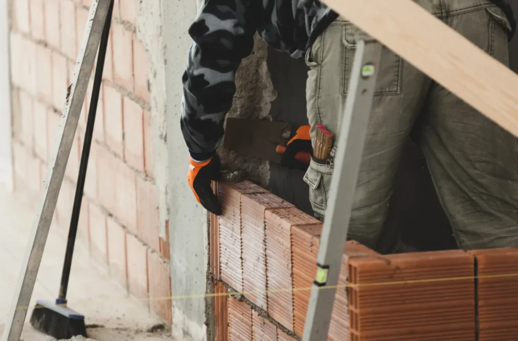 Construction worker laying bricks with mortar on a building site