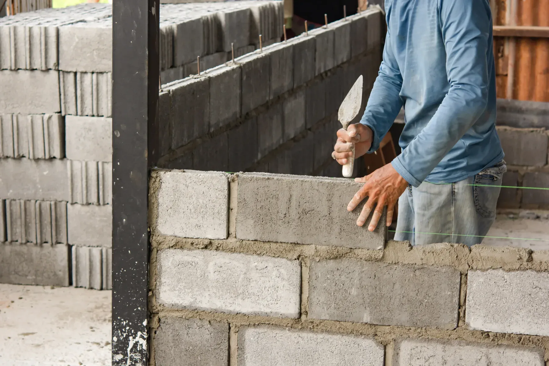 Man building a wall with concrete blocks and mortar