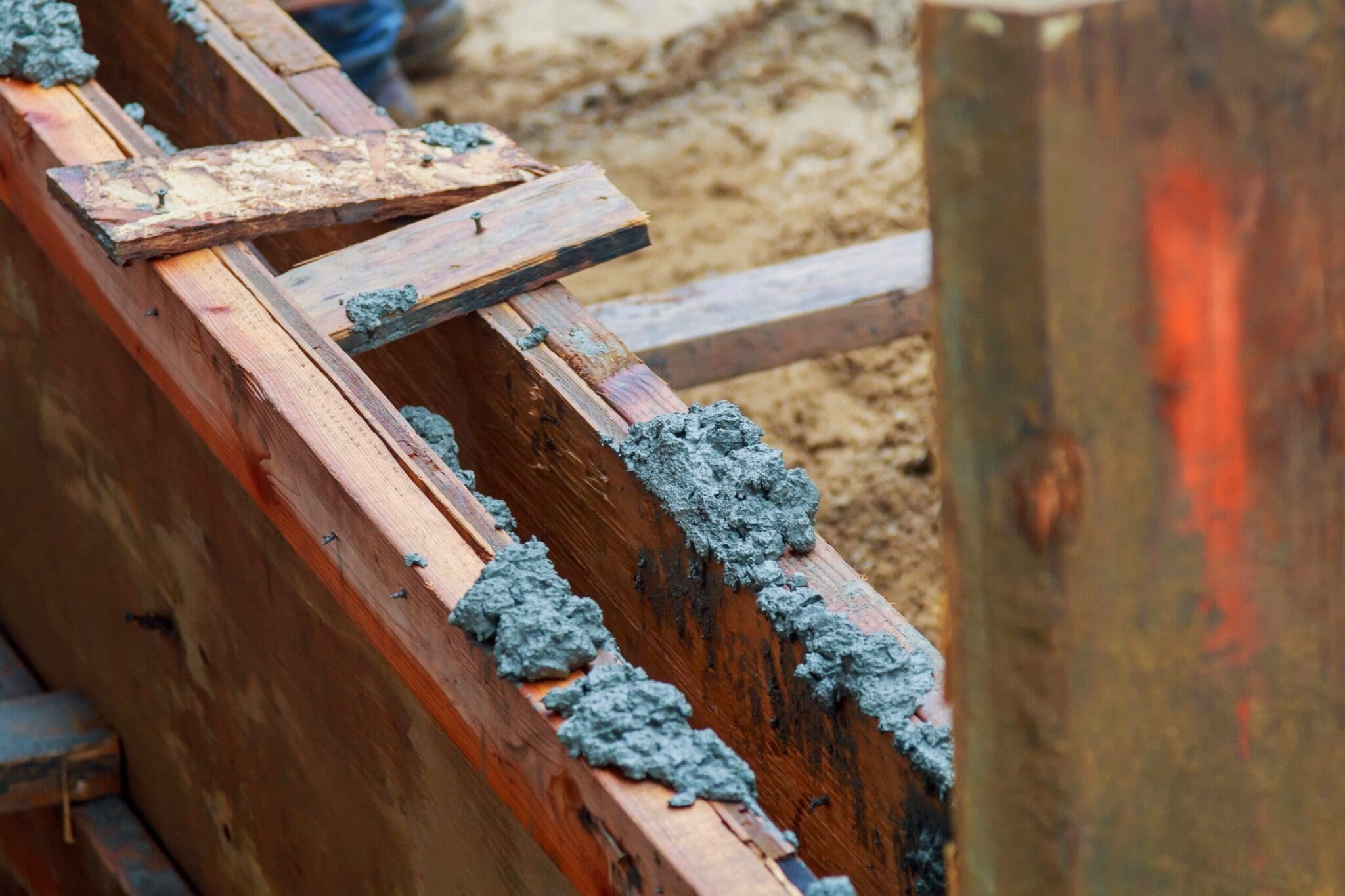 Close-up of wooden concrete forms with fresh concrete oozing out.