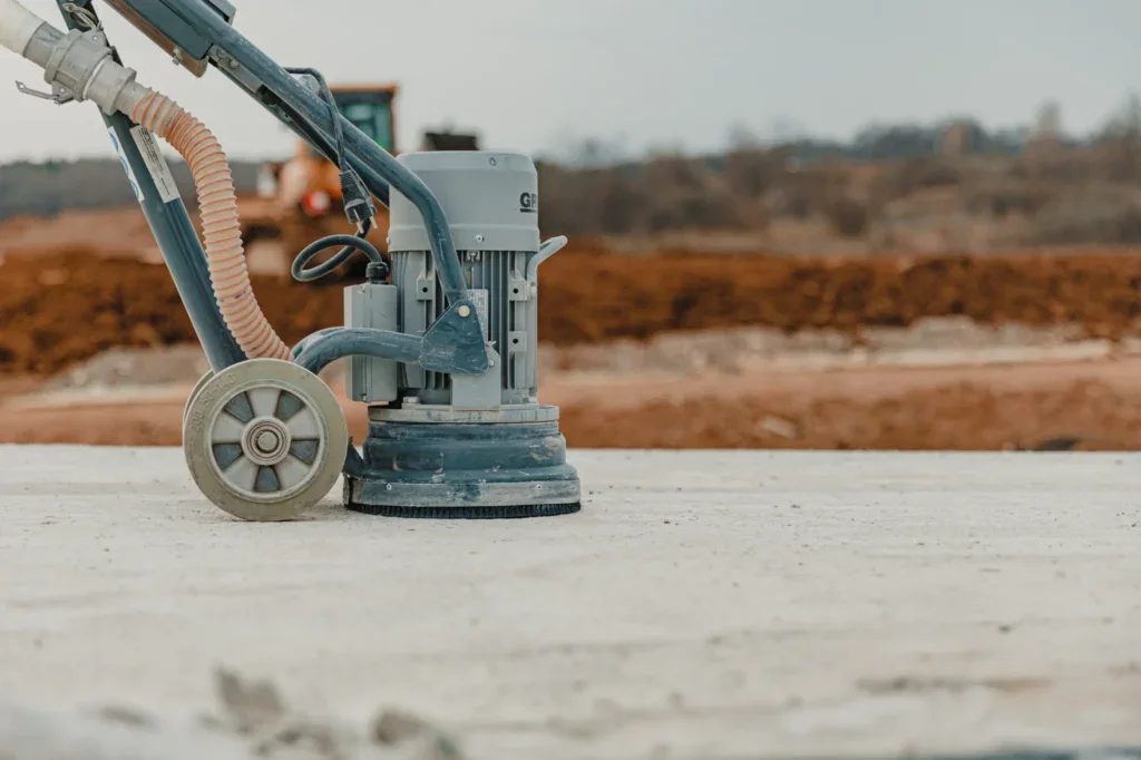 Concrete grinder on a light grey concrete surface with blurred background