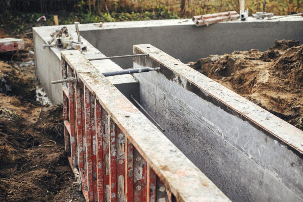 Concrete foundation with formwork and rebar at a construction site.