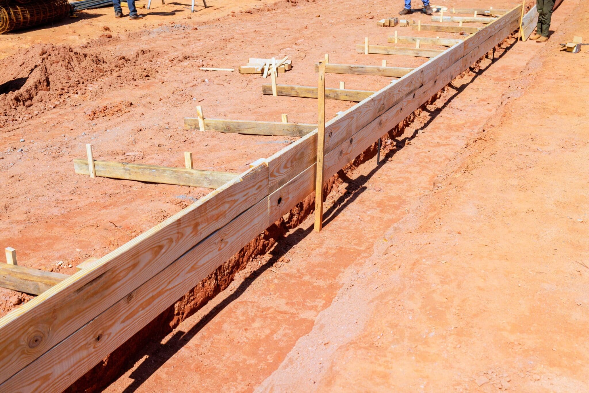 Wooden forms for concrete on a dirt construction site with workers.