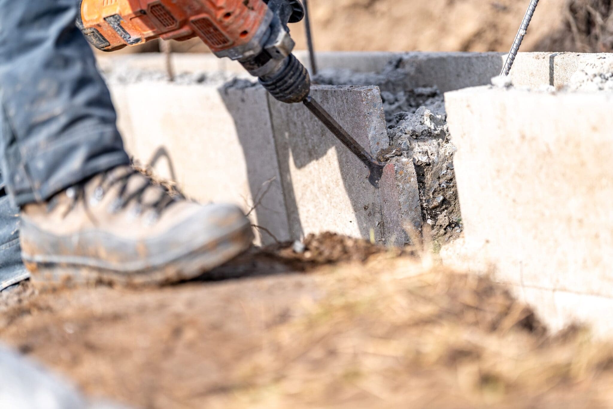 Person using a jackhammer to break concrete on a construction site.