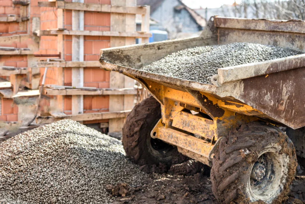 A construction site with a yellow dump truck full of gravel