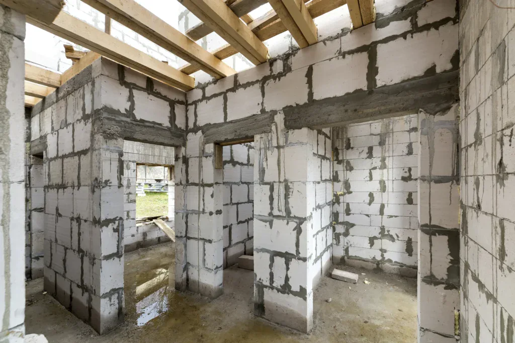 Interior of a house under construction with white brick walls and wooden beams