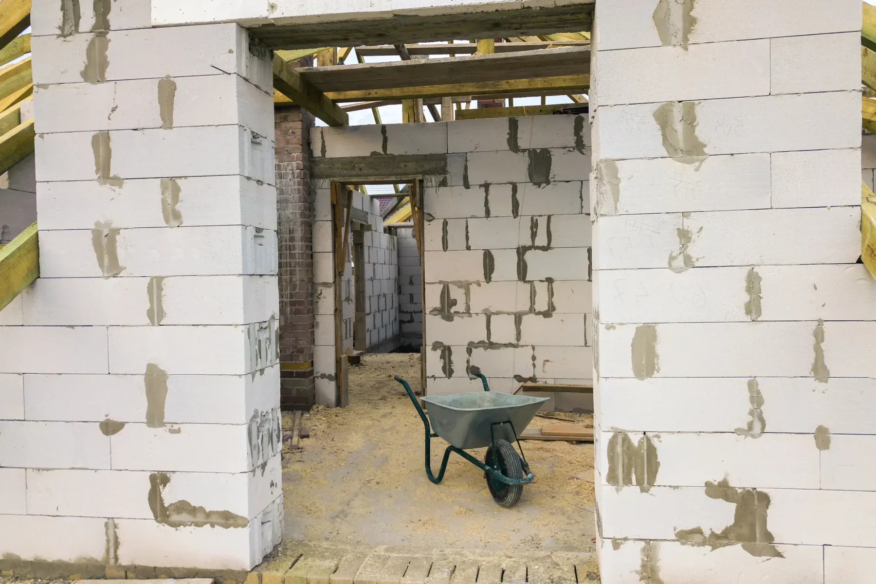 Unfinished house interior with white brick walls and a wheelbarrow.