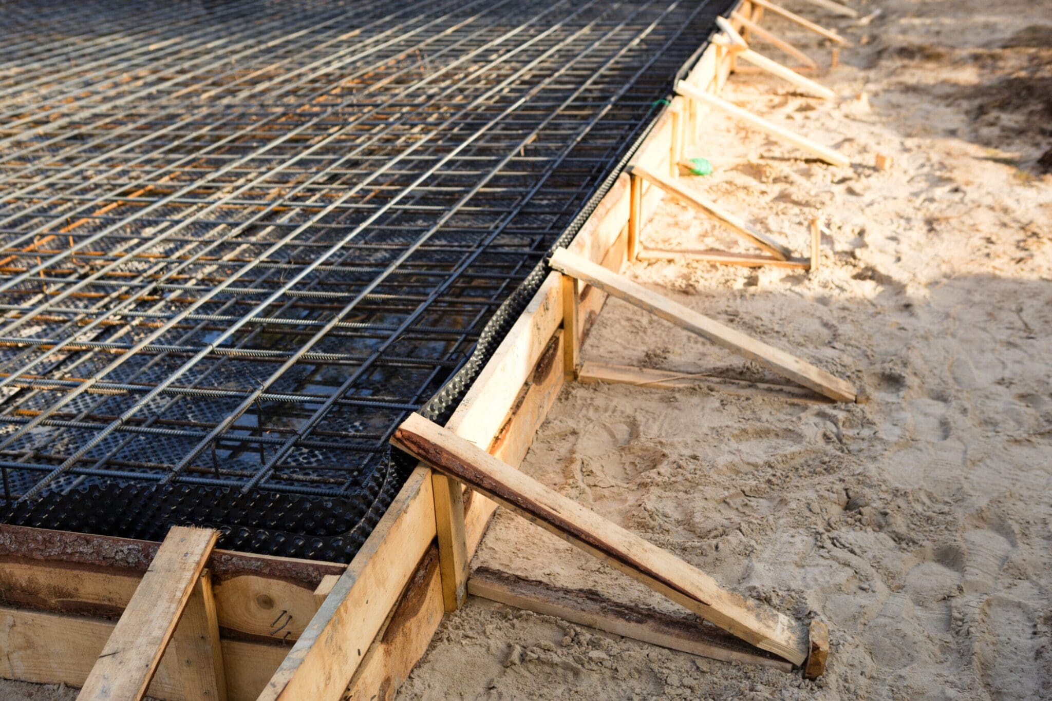 Foundation with rebar grid and wooden formwork on sandy ground