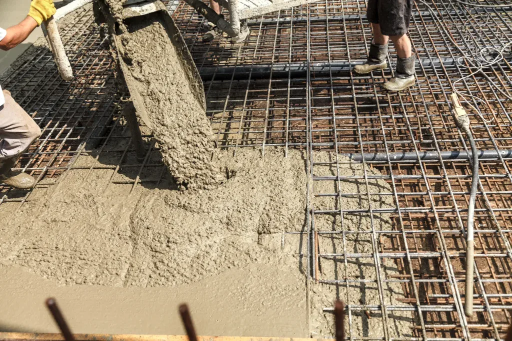 Concrete being poured from a chute onto a rebar grid.