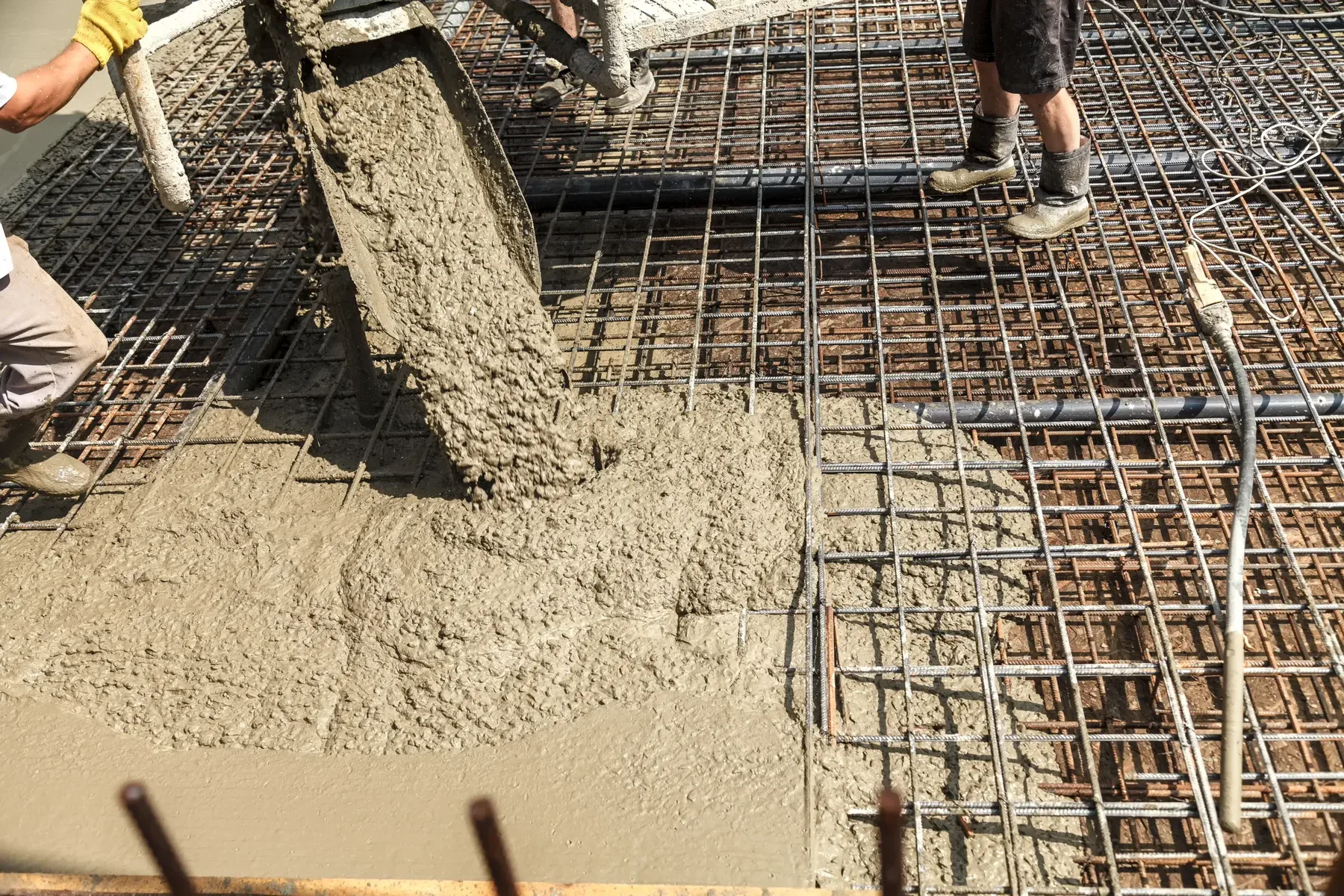 Concrete being poured from a chute onto a rebar grid.