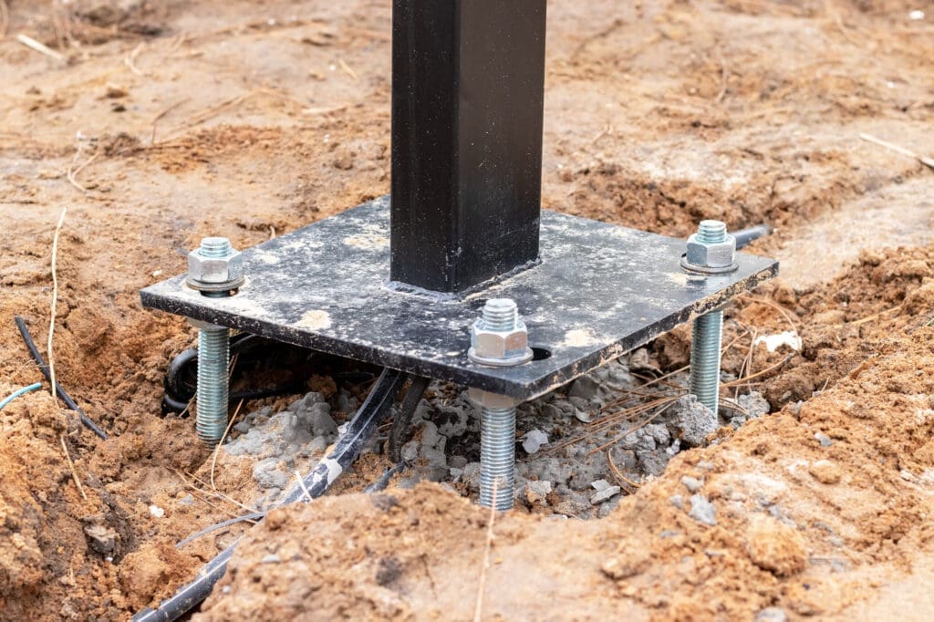 Black metal post anchored to the ground with bolts and nuts