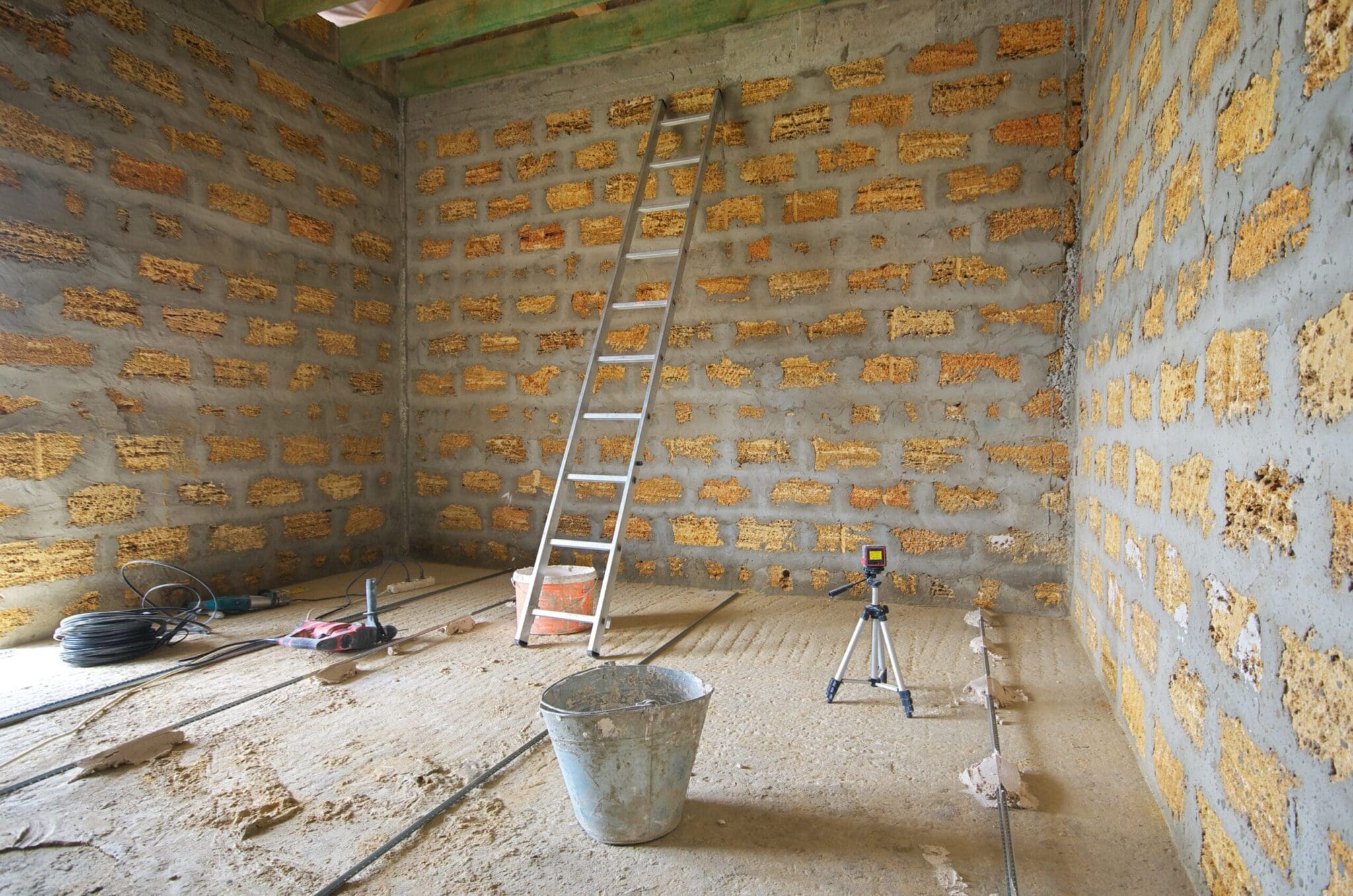 Interior room under construction with concrete walls and a ladder.