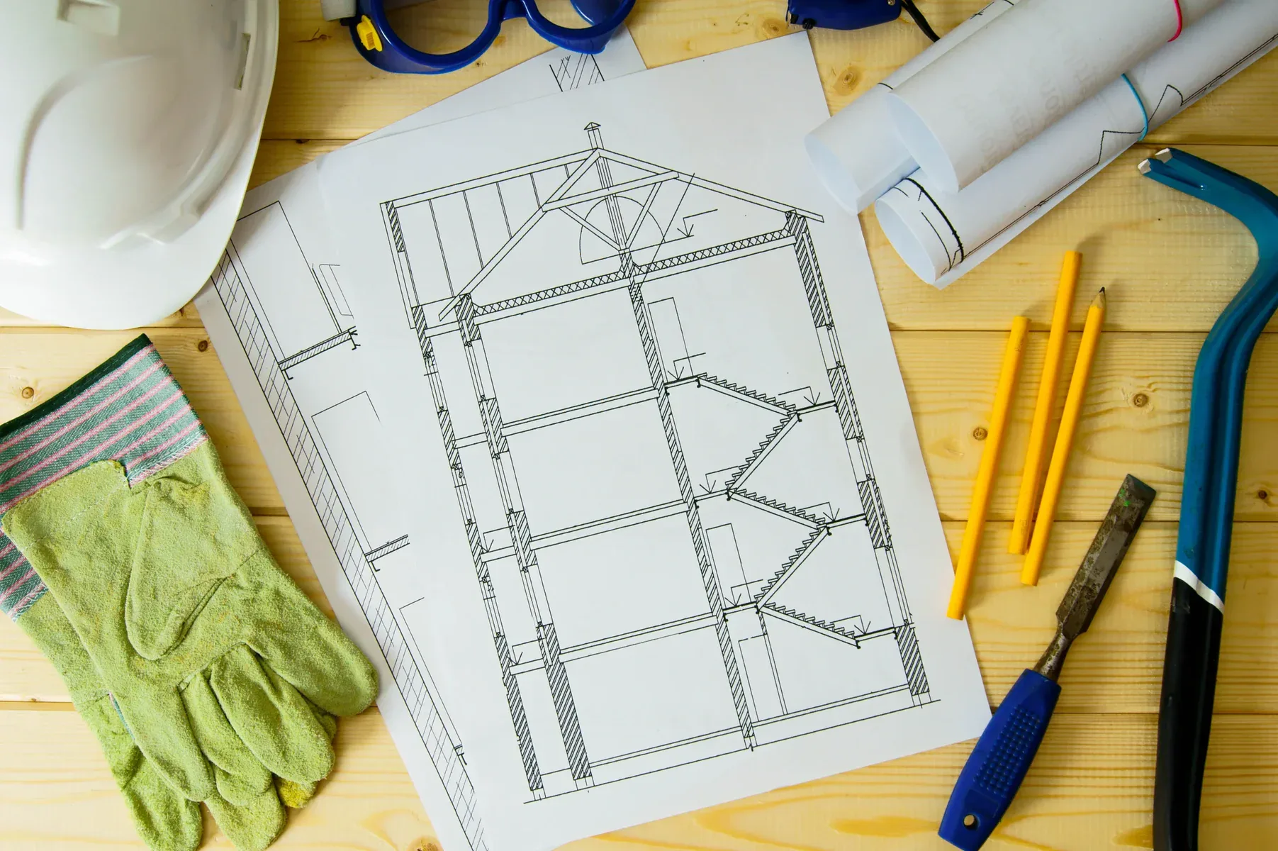 Architectural blueprints, safety gear, and tools on a wooden surface