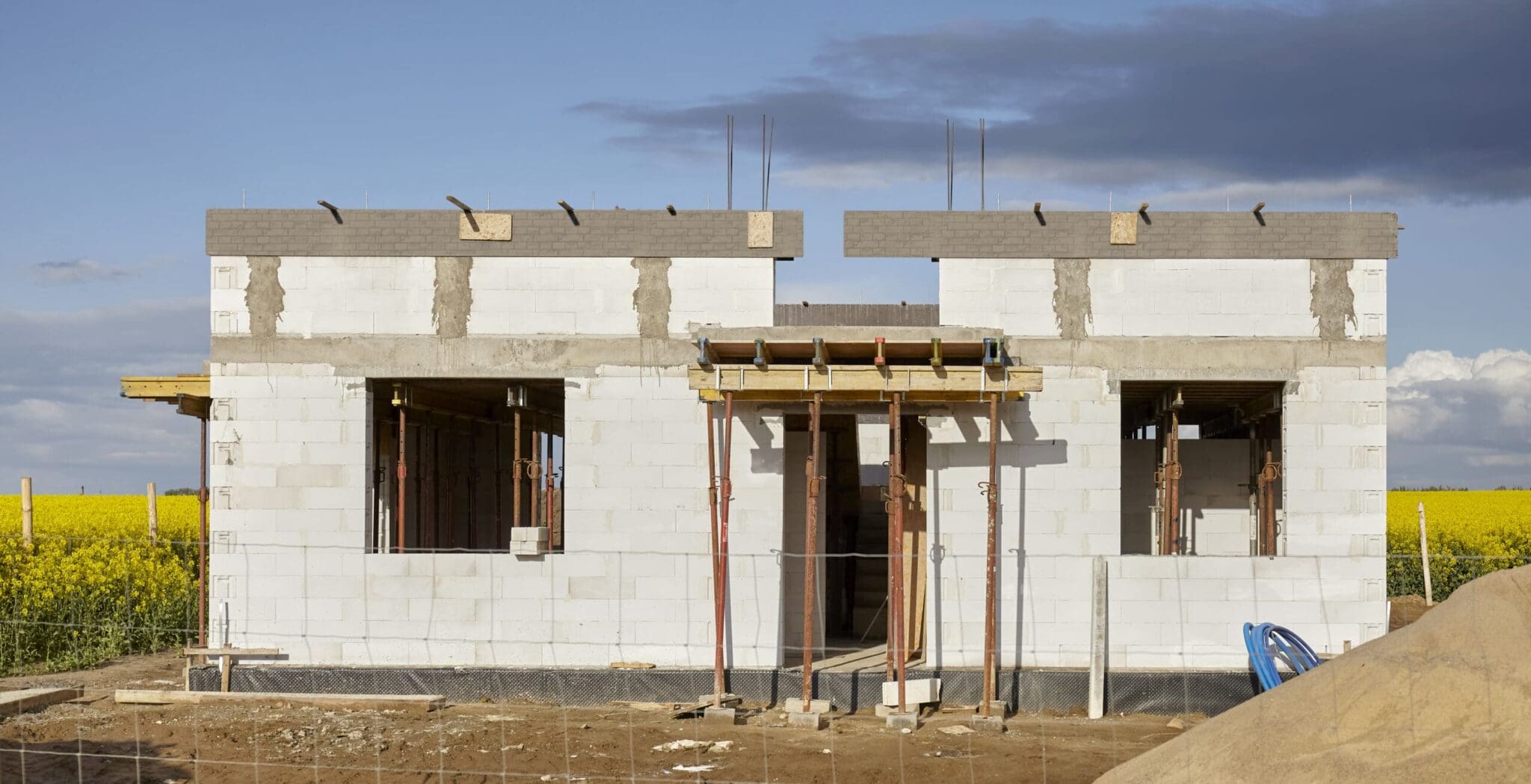 Unfinished house construction with white blocks and yellow field.