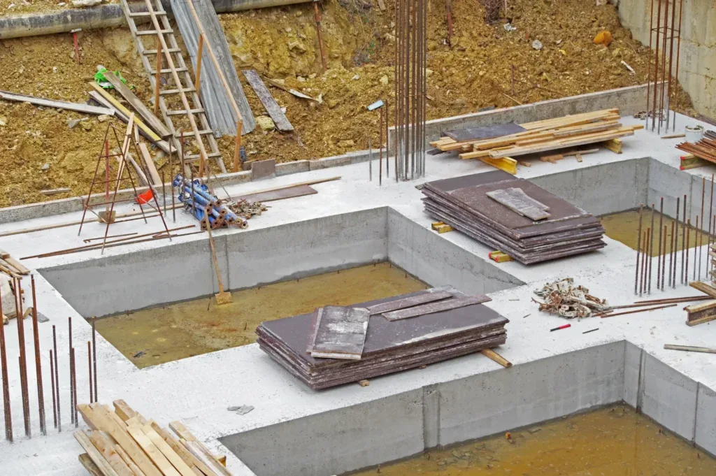 Construction site with concrete foundation, rebar, and wooden planks.