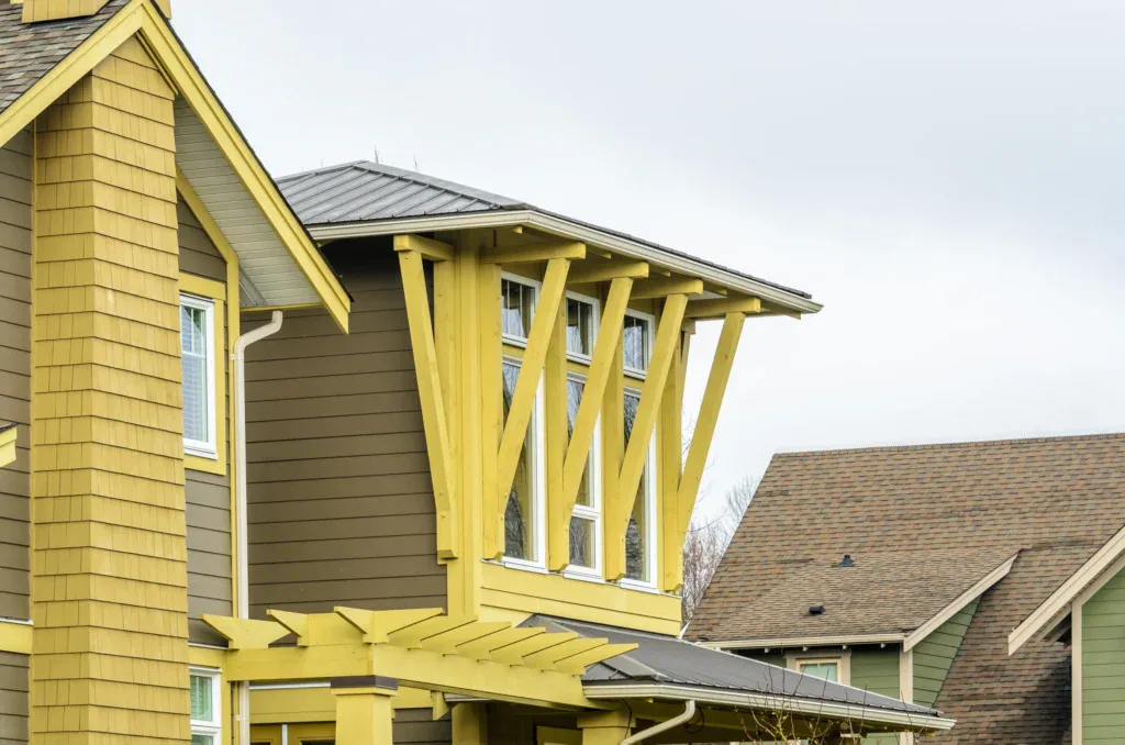 Modern house with yellow and brown siding under a cloudy sky.