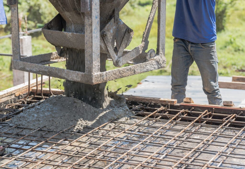Concrete pouring from a mixer onto a rebar-reinforced slab.