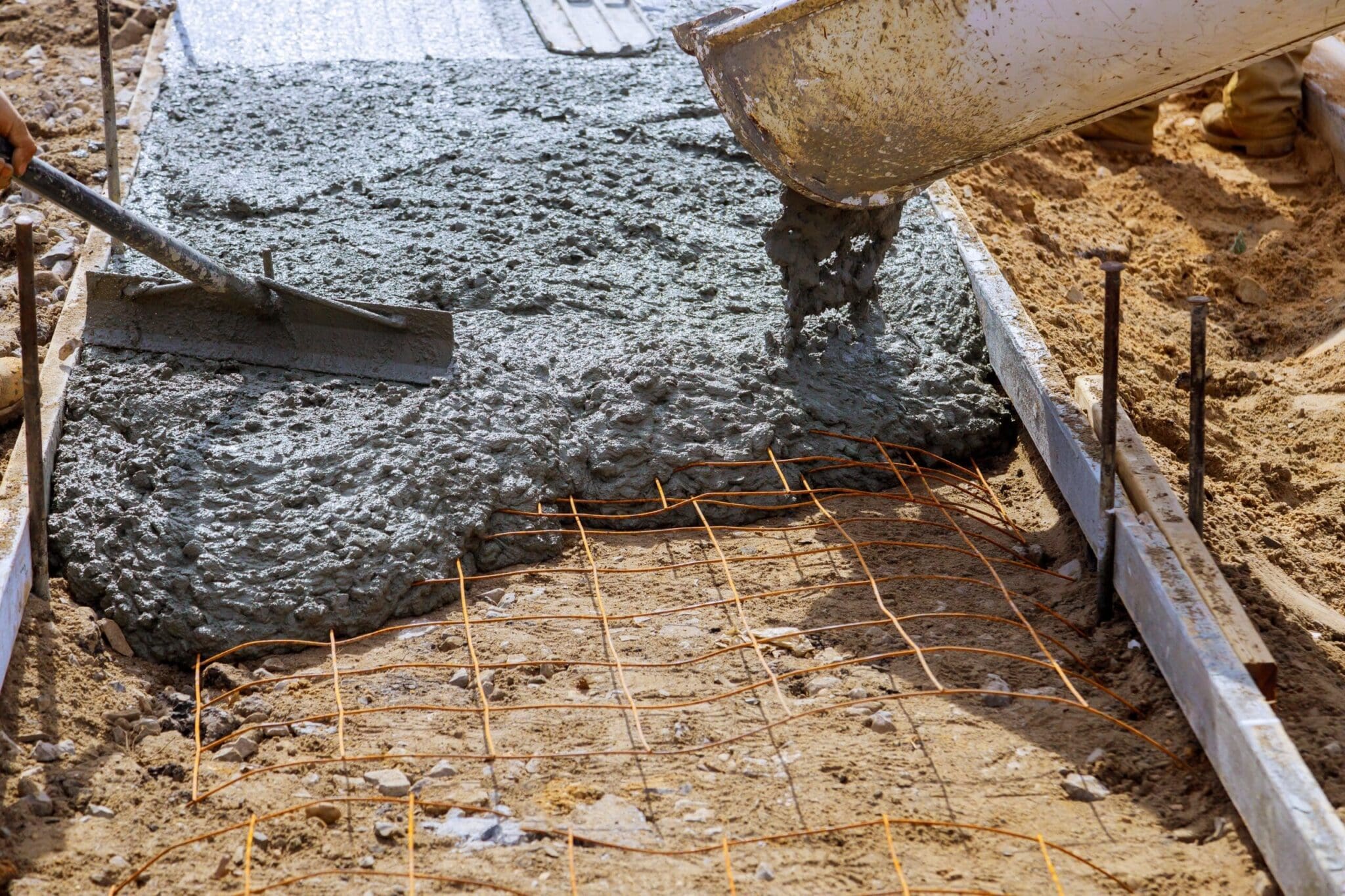 Wet cement being poured onto a wire mesh frame for a concrete slab.