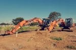 Excavators at a construction site with Graham Harris branding in New Zealand.