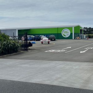 Modern farm supply store with parking lot in rural New Zealand setting.
