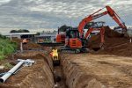 Excavator digging trench for plumbing on construction site.