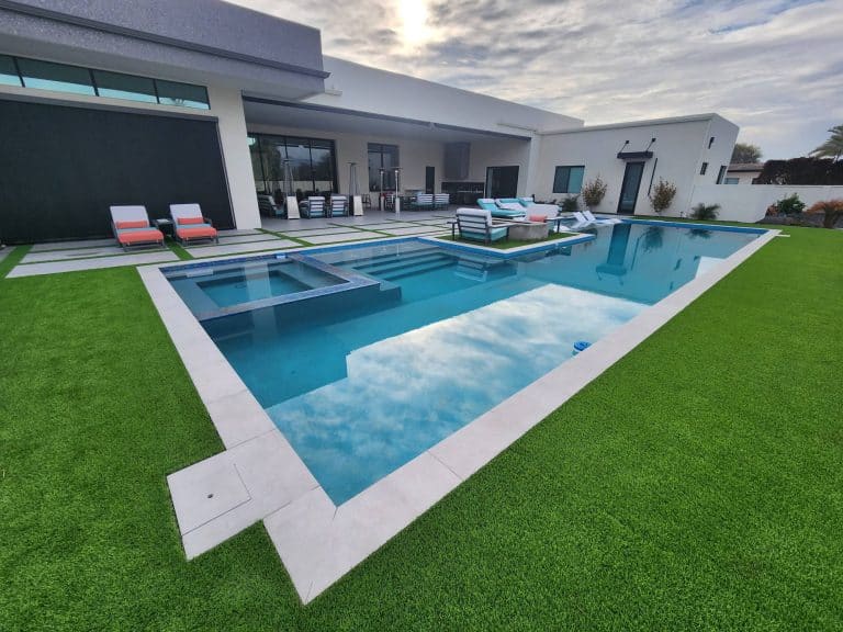 Elegant residential swimming pool with landscaped yard and outdoor lounging area.