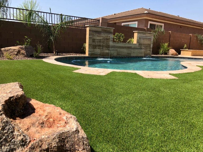 Beautiful backyard landscape design with pool, water feature, and lush greenery in Arizona.