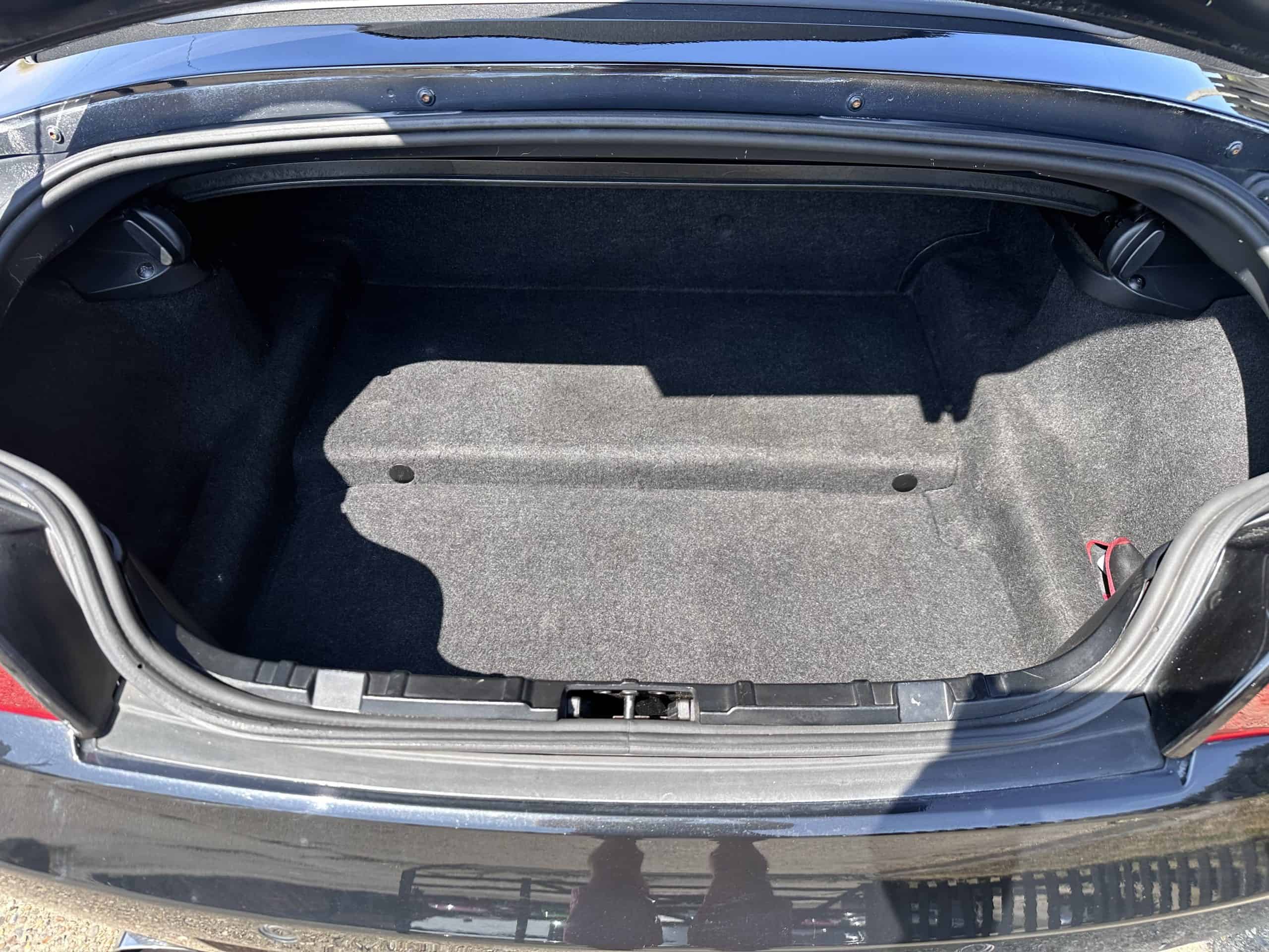 Spacious trunk of a black BMW Z4 convertible with subtle red features.
