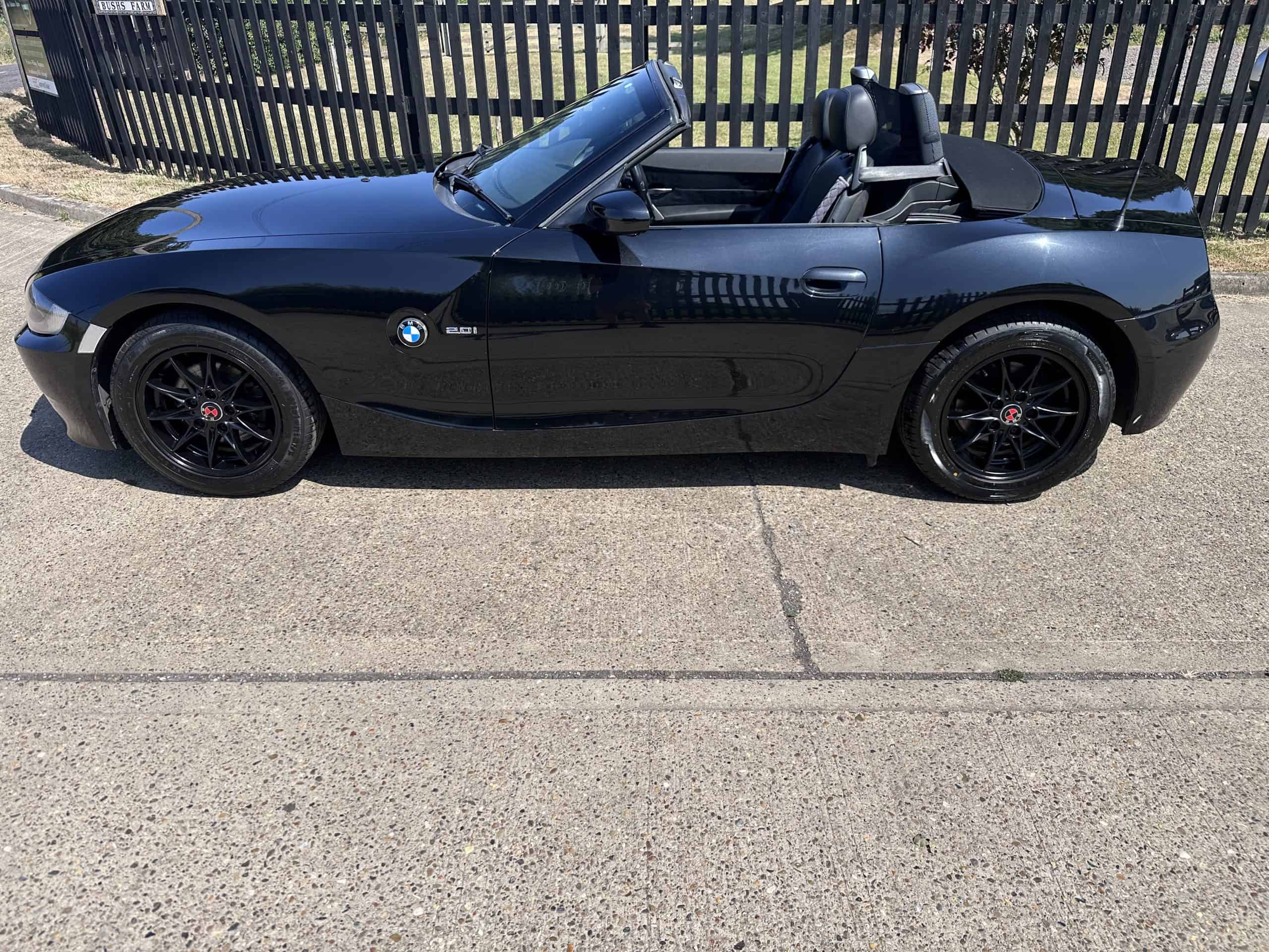 Black BMW Z4 convertible with subtle red features and open top.