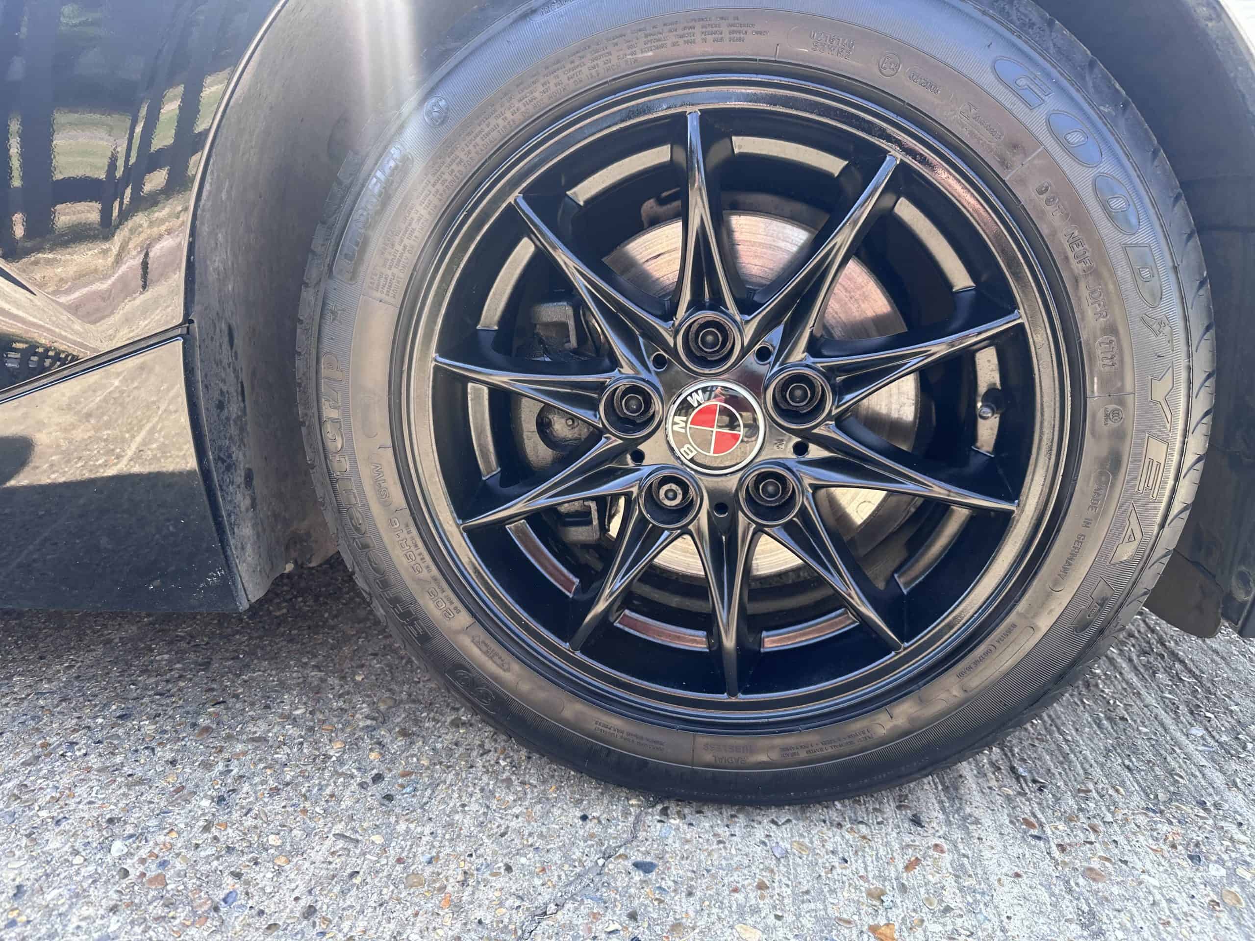 Close-up of black alloy wheel with red center cap at Greens Garage Suffolk.